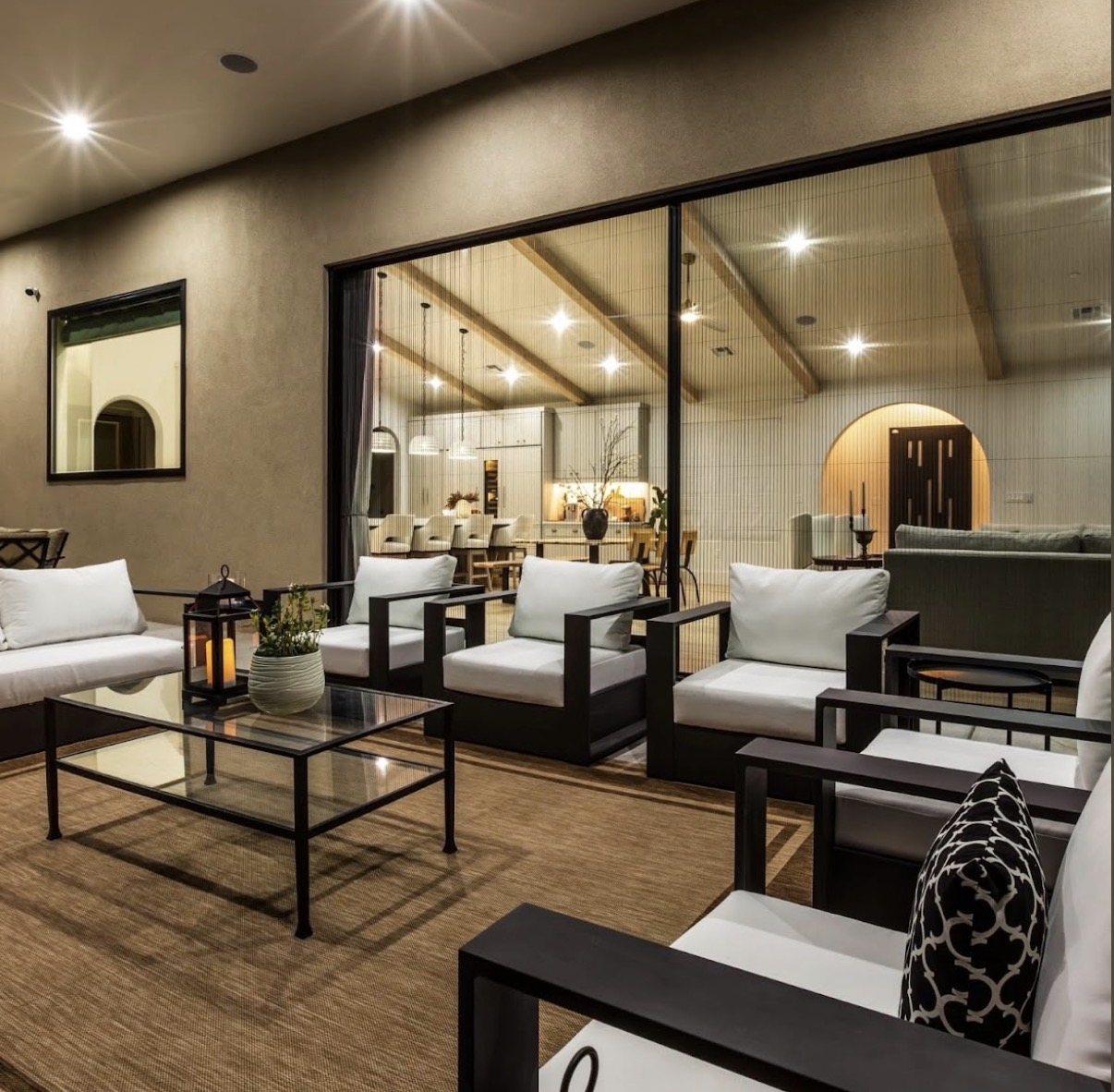 Covered outdoor living room connected to a custom home through expansive glass doors